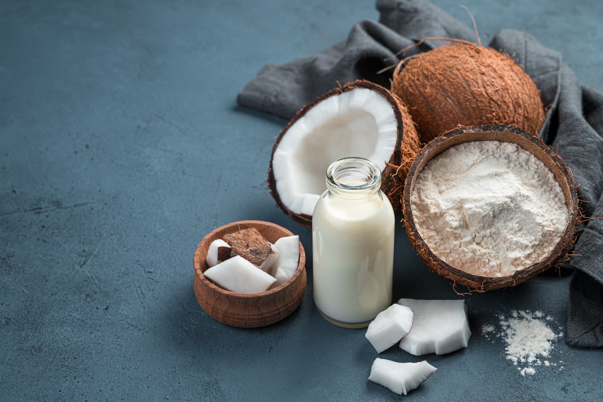 Coconut milk, flour and coconuts on a blue background